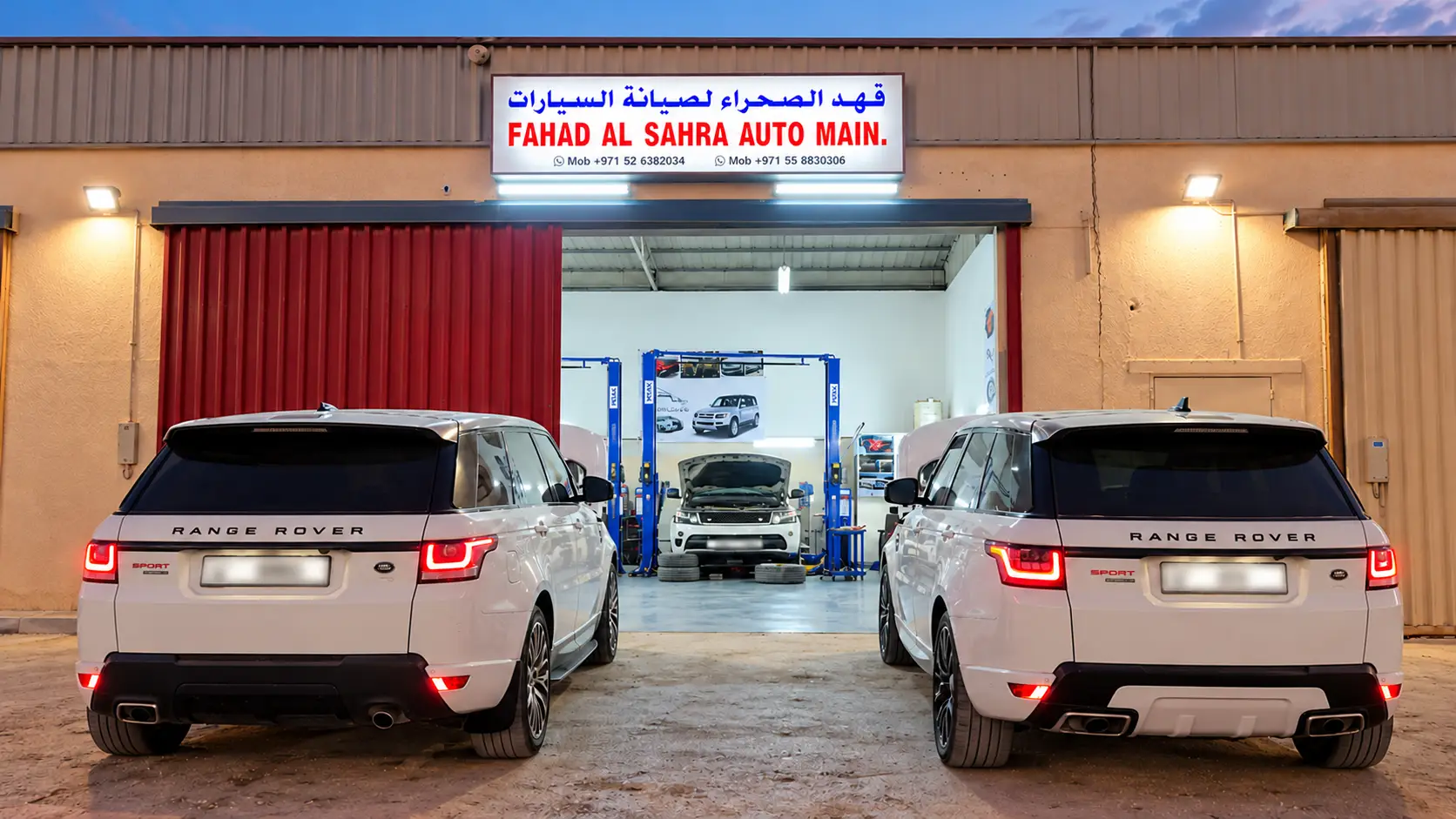 Fahad Al Sahra Range Rover garage in Sharjah at dusk, two Range Rover Sport outside and a Range Rover on the lift inside